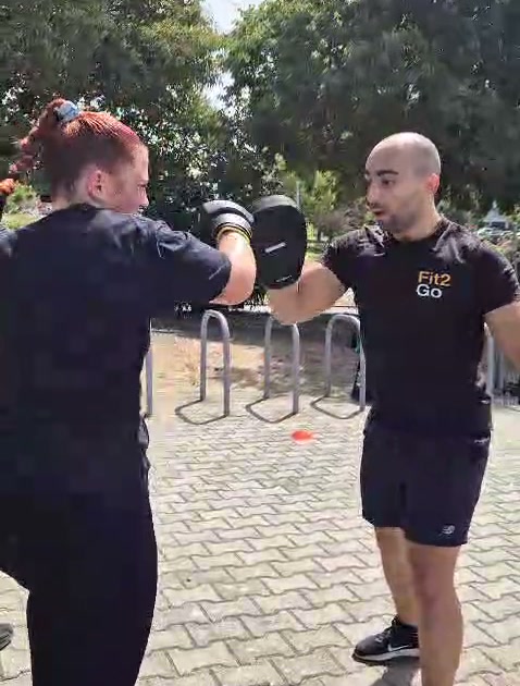 Treinador da Fit2Go a segurar manoplas para uma participante